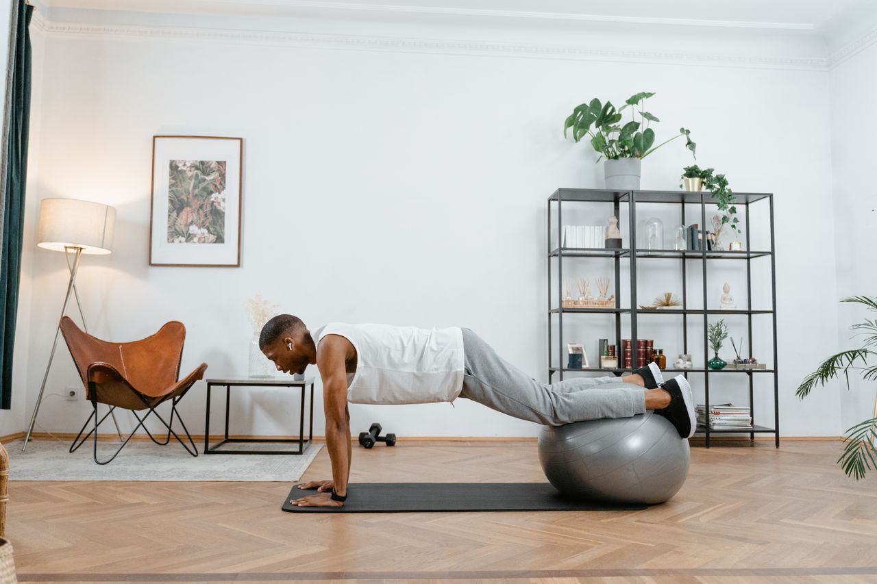 Adult man working out with stability ball indoors, promoting a healthy lifestyle.